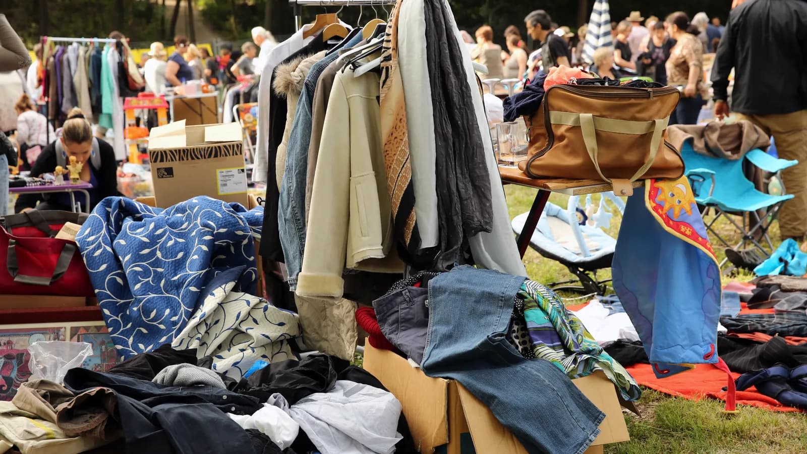 Flohmarktstand mit Kleiderstange, Taschen und Kartons voller Kleidung